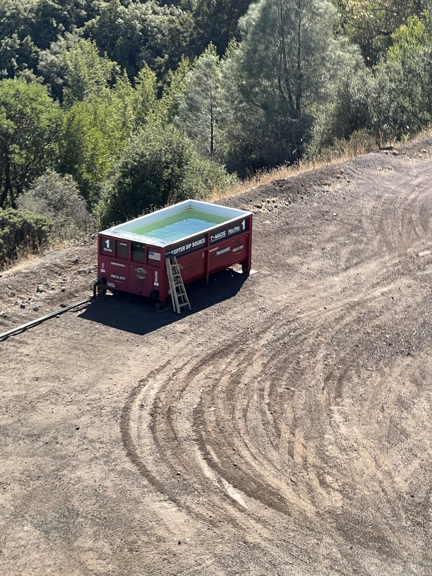 A red dip container sitting on bare dirt as seen from above.