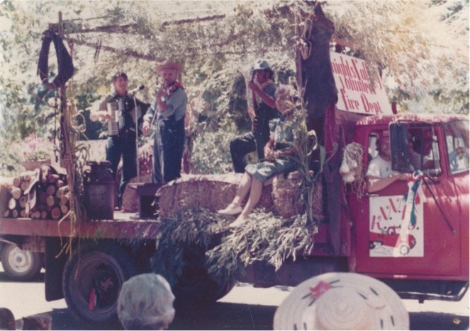 A festive parade float with musicians, hay bales, and decorations, labeled "Knights Landing Fire Dept."