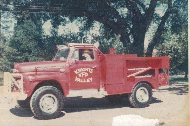 A vintage red fire truck with "KNIGHTS VFD VALLEY" on the side, parked under trees.