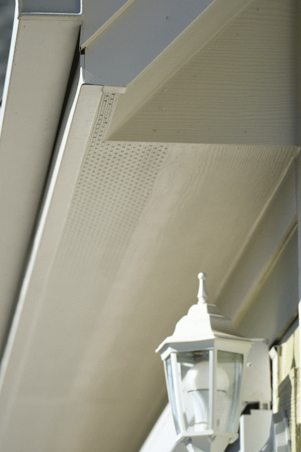 A white outdoor lamp on a house siding under the eaves.