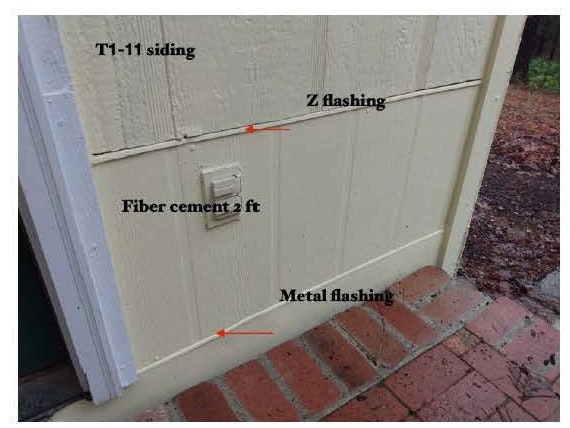 Wall with T1-11 siding, fiber cement, Z and metal flashing above brick; electrical outlet visible.
