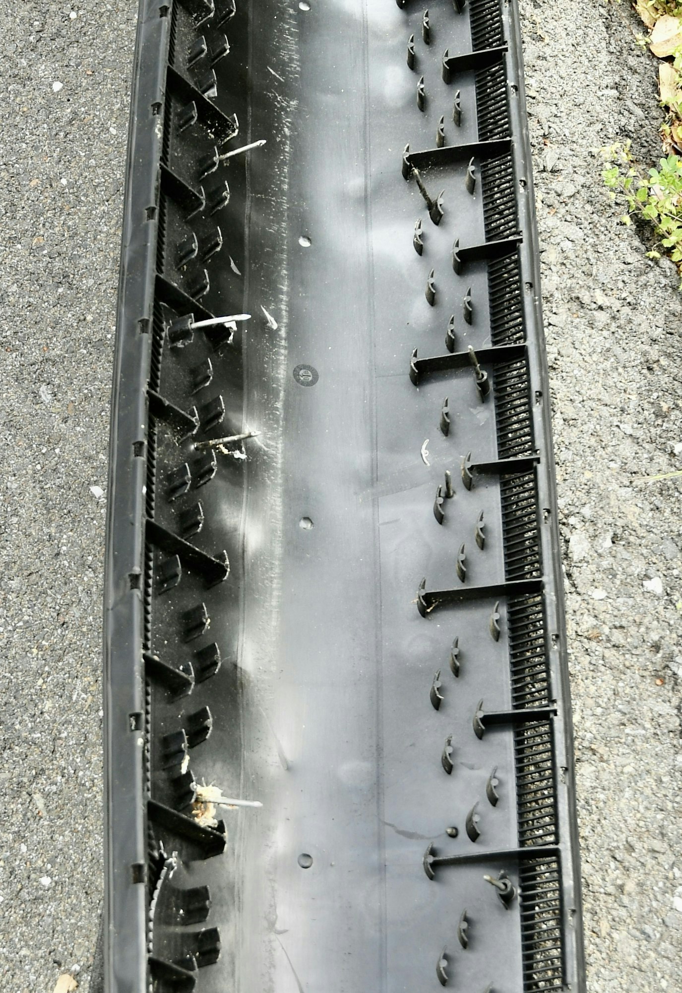 A damaged, punctured car tire with protruding screws.