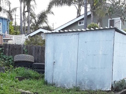 A stack of tires next to a backyard shed.