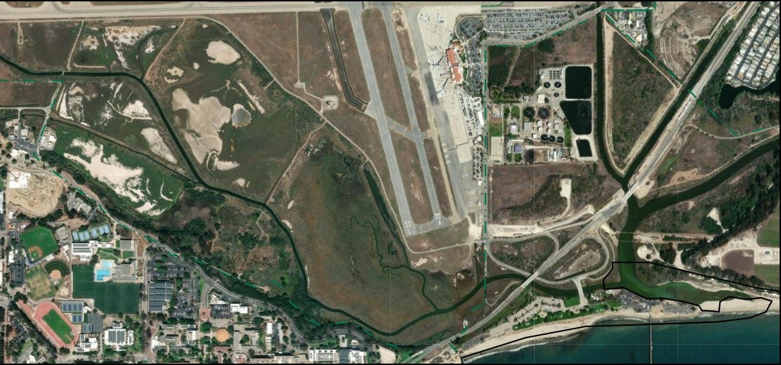 The image shows an aerial view of the Goleta Slough between Santa Barbara Airport and UC Santa Barbara, and the mouth of the Slough at Goleta Beach. .