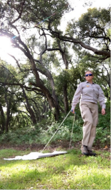 A vector technician dragging a cloth on the ground to pick up ticks.