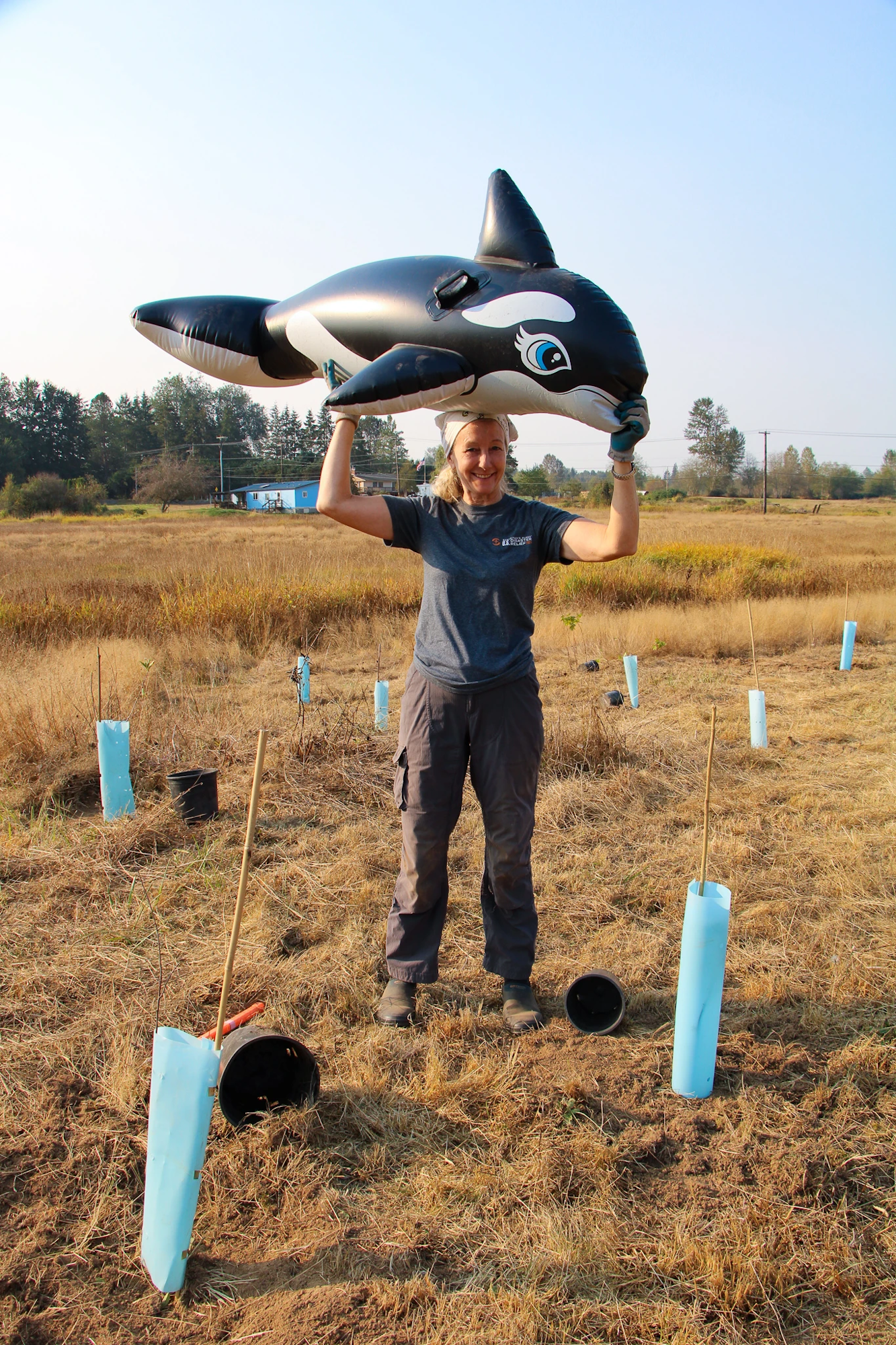 A person in a field holding an inflatable orca above their head.