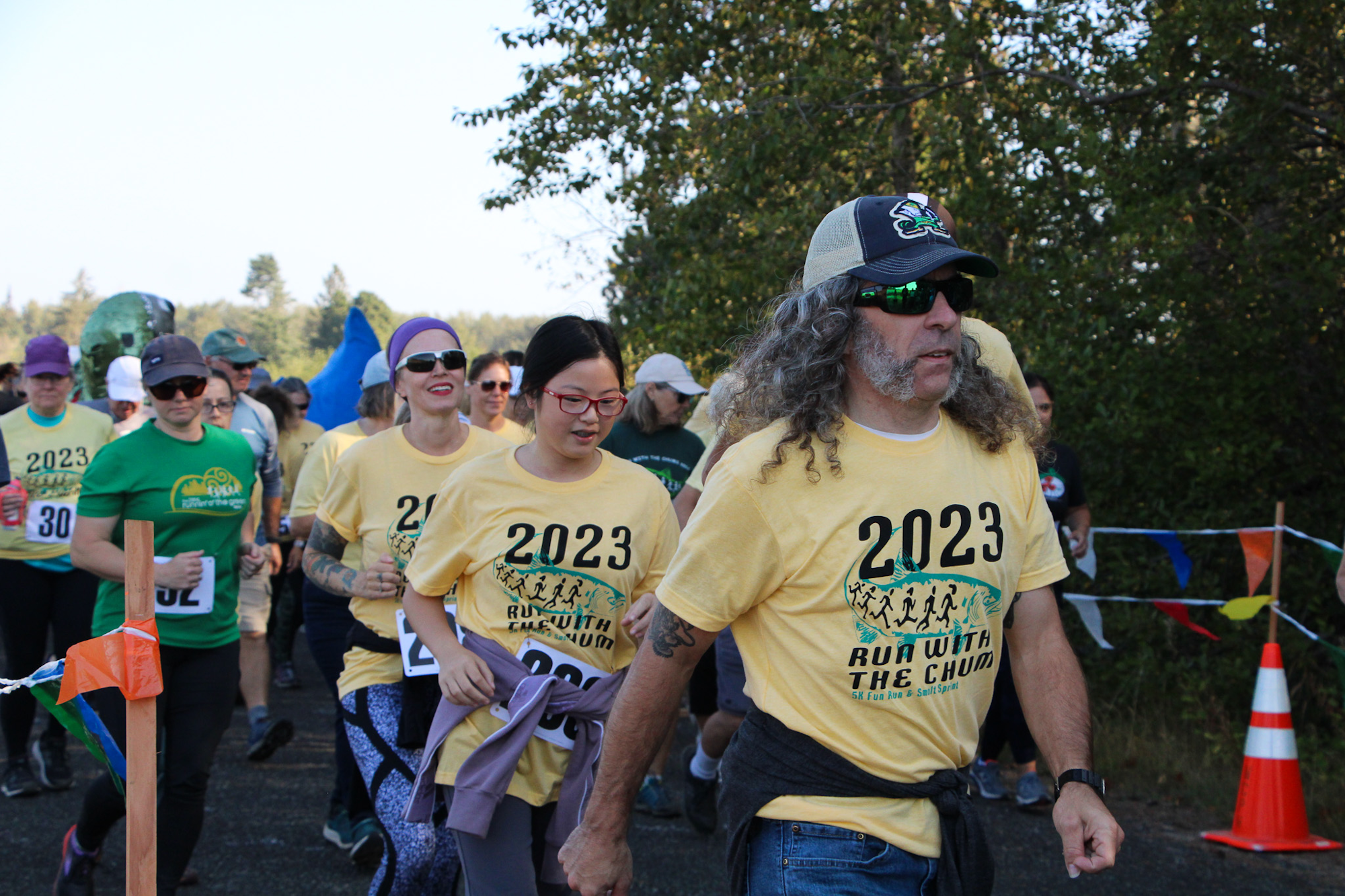 People in yellow shirts participating in a 5K run event titled "Run with the Chums" in 2023.