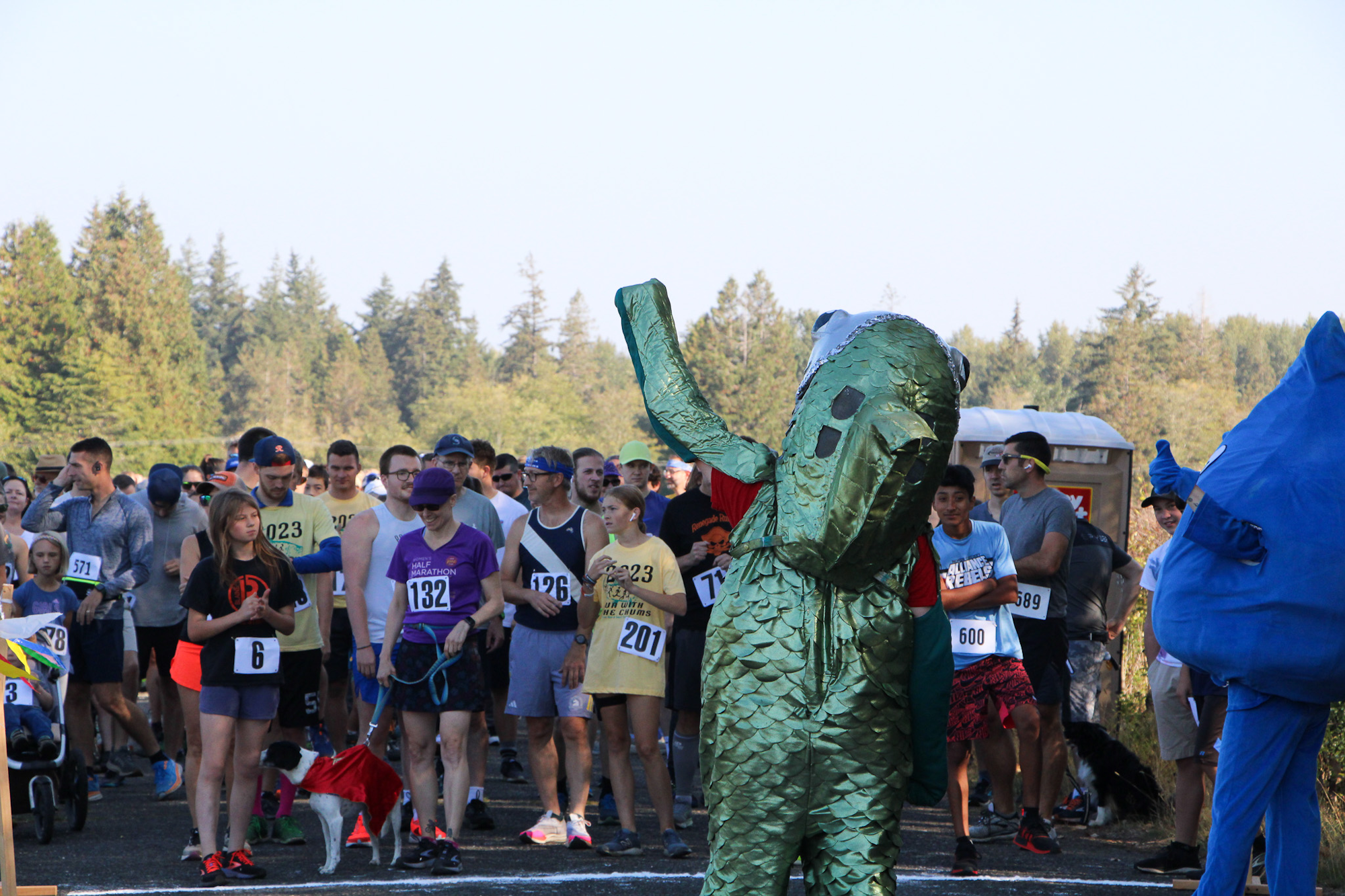 A crowd of people at a race start line, with some in costumes, including green and blue mascots.