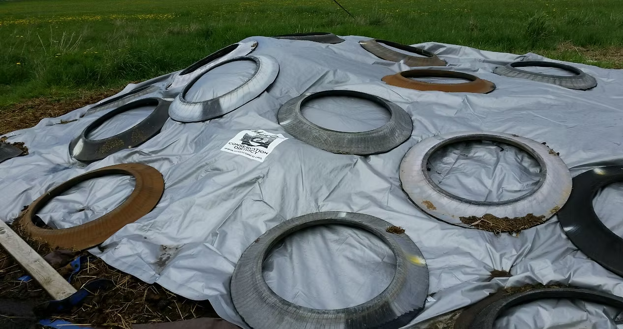 Tires on a tarp in a field with a conservation district label.