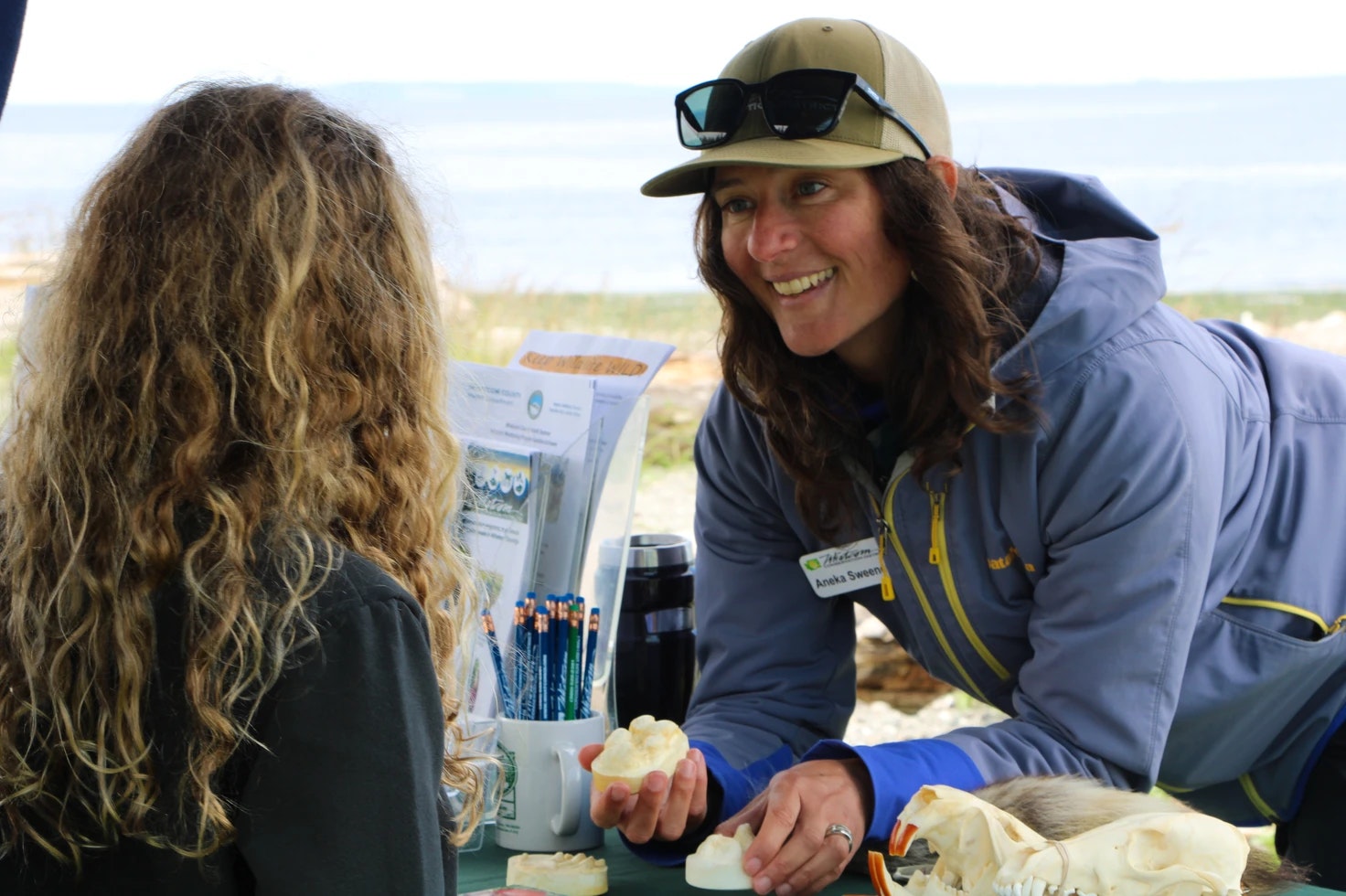 Two people interact at an outdoor educational exhibit with nature-themed items.