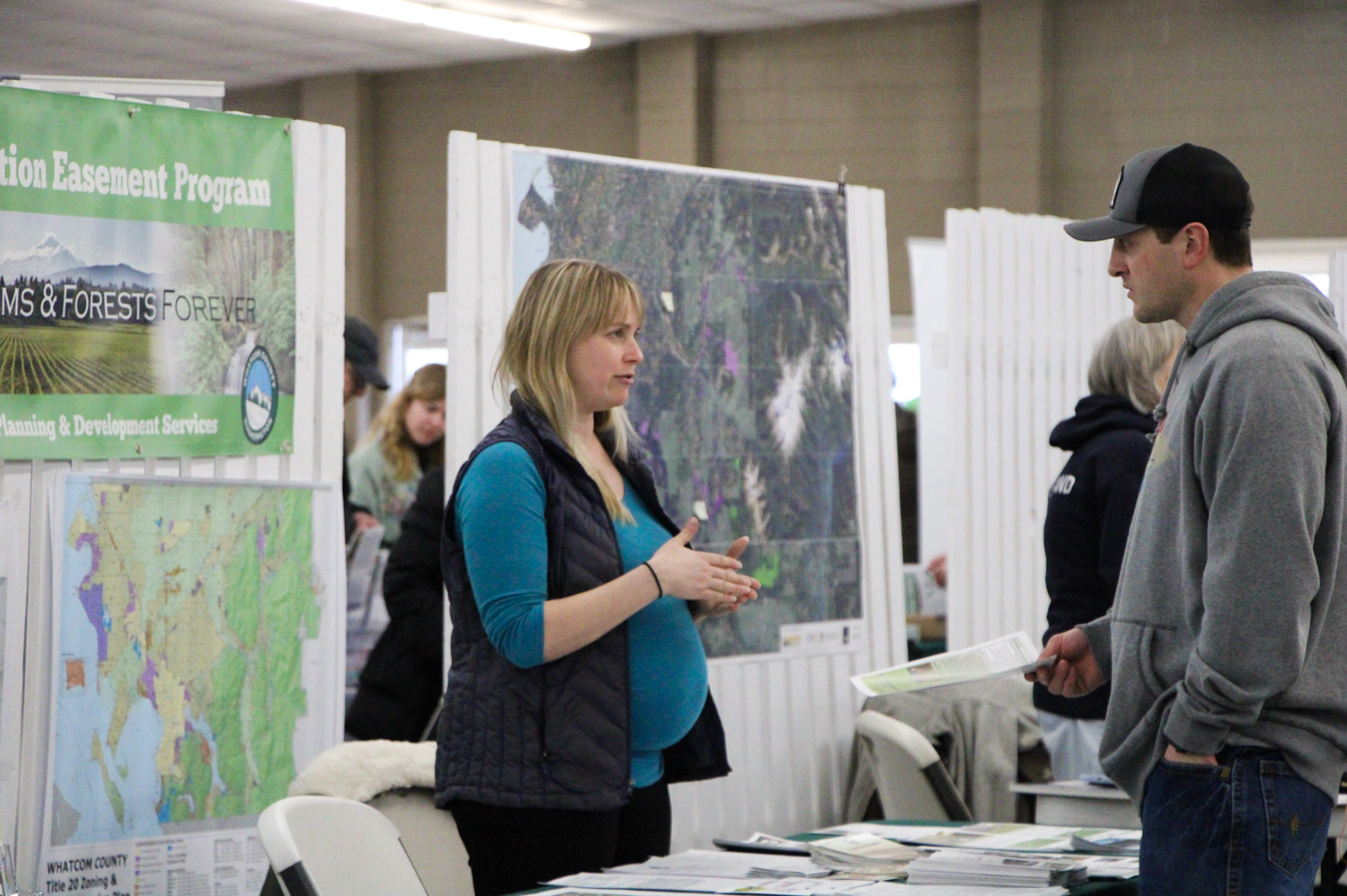 Two people conversing at an information booth with maps and brochures about a conservation easement program.