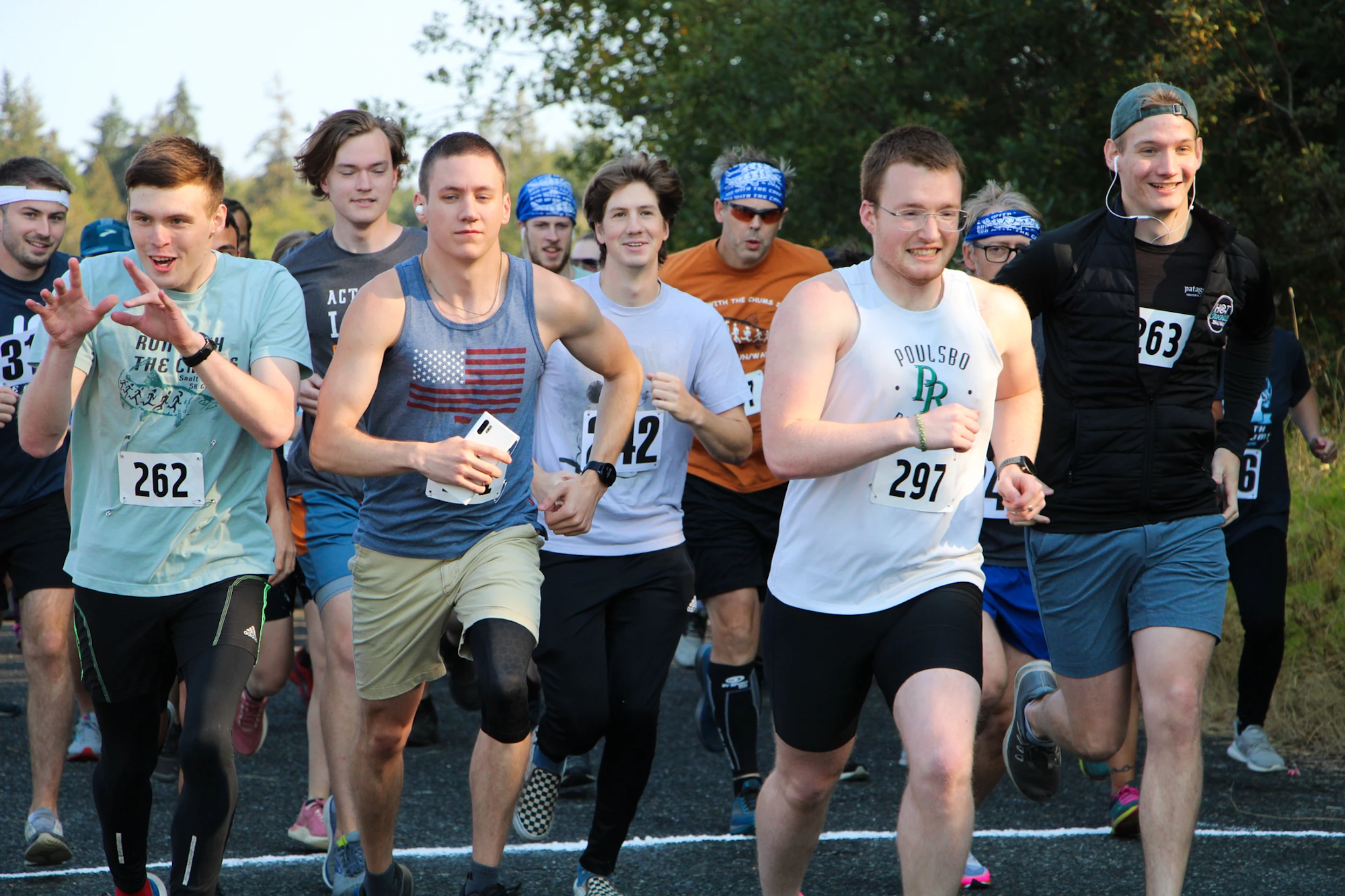 A group of runners starting a race, wearing numbered bibs.
