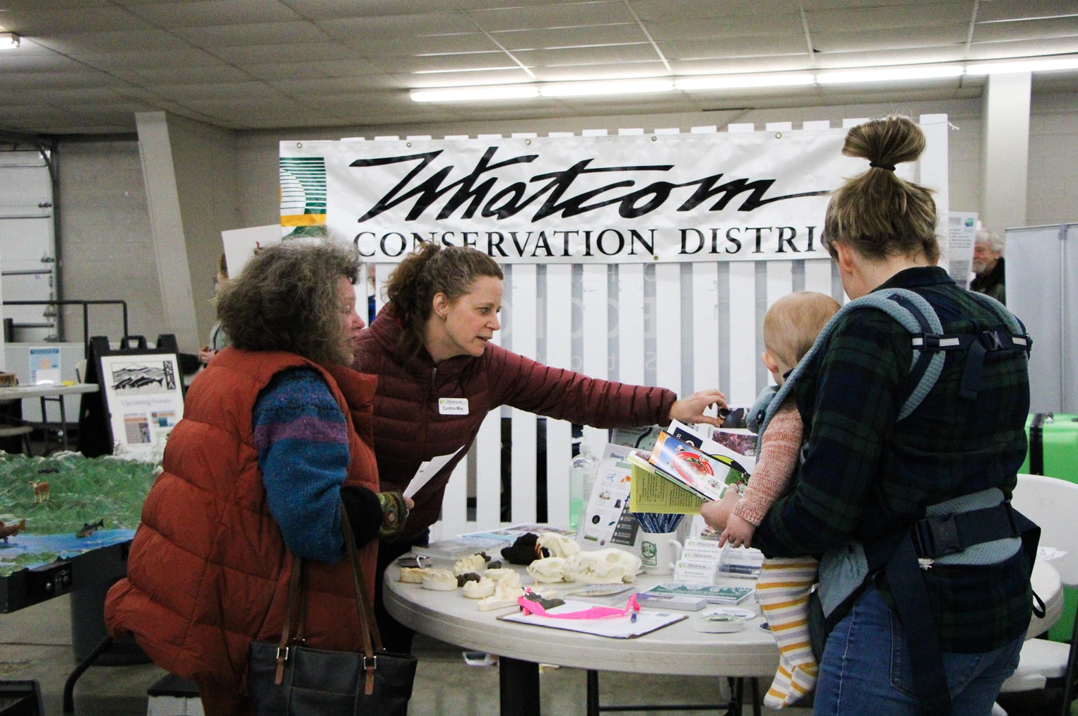 People at a conservation booth discussing materials.
