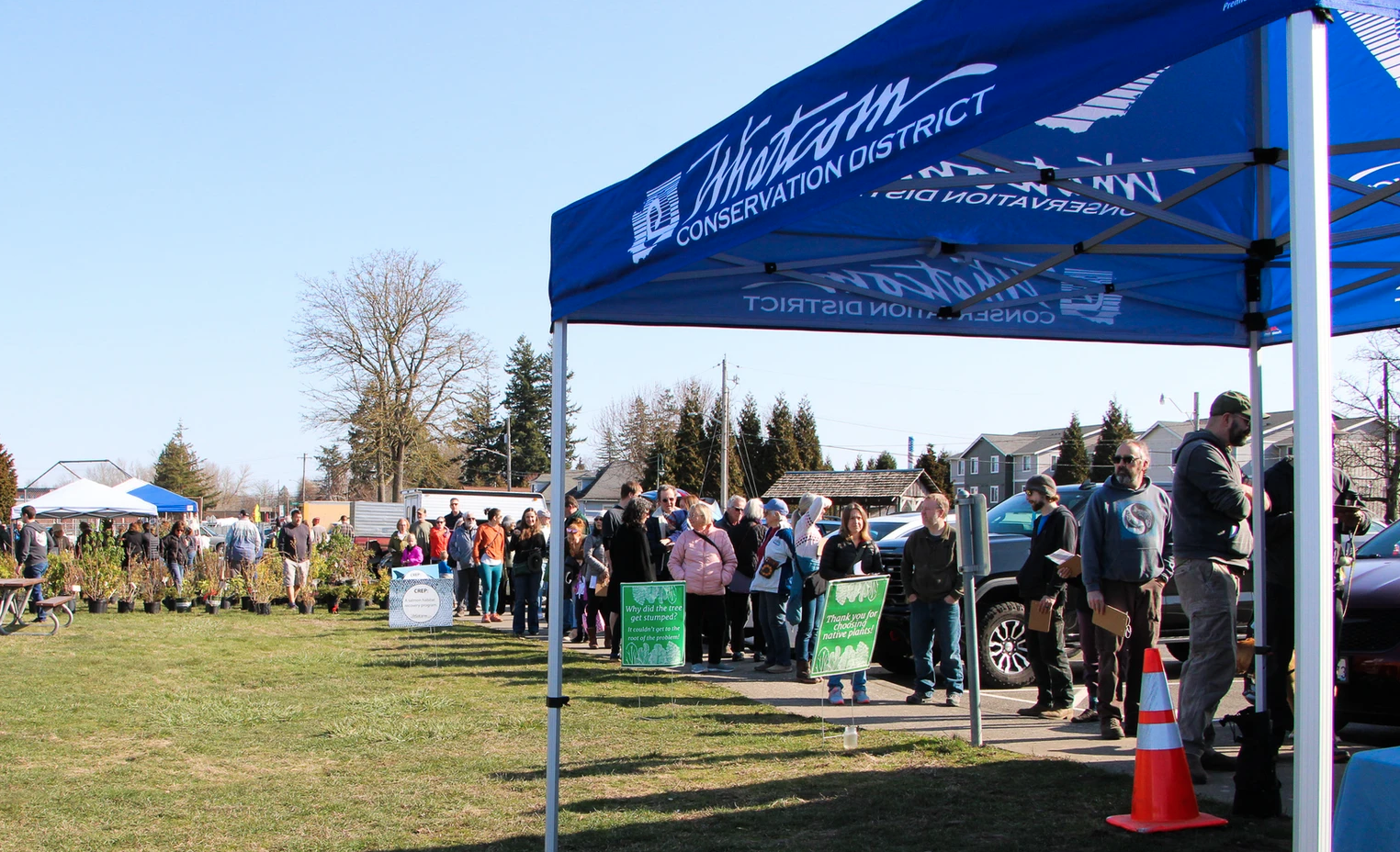 People lining up under a tent at an outdoor event, likely related to conservation.