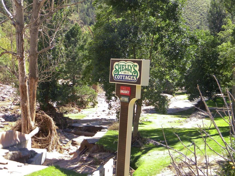 Photo of flood damaged land and a sign for Shelly's Cottages: 20130918-2013-09-18 11.54.28