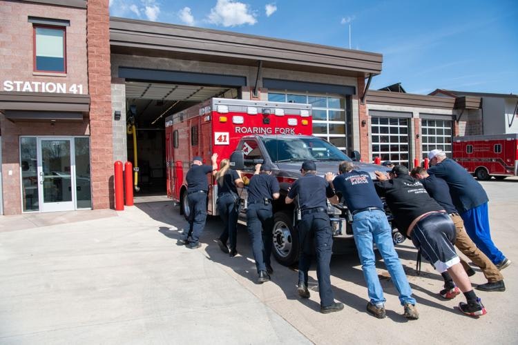 People pushing a fire truck at "STATION 41" with another emergency vehicle inside.