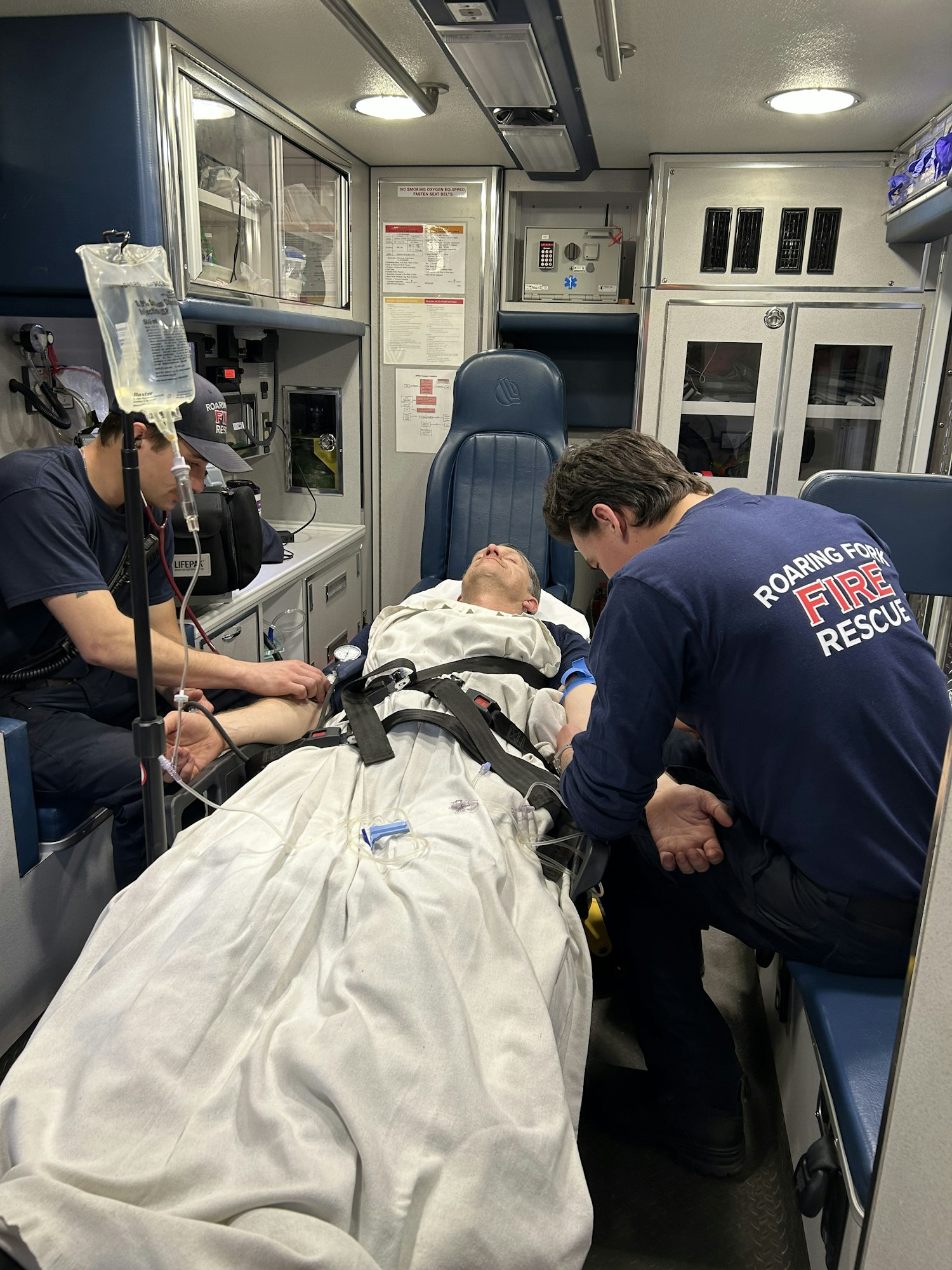 Patient in an ambulance with EMTs providing medical care.