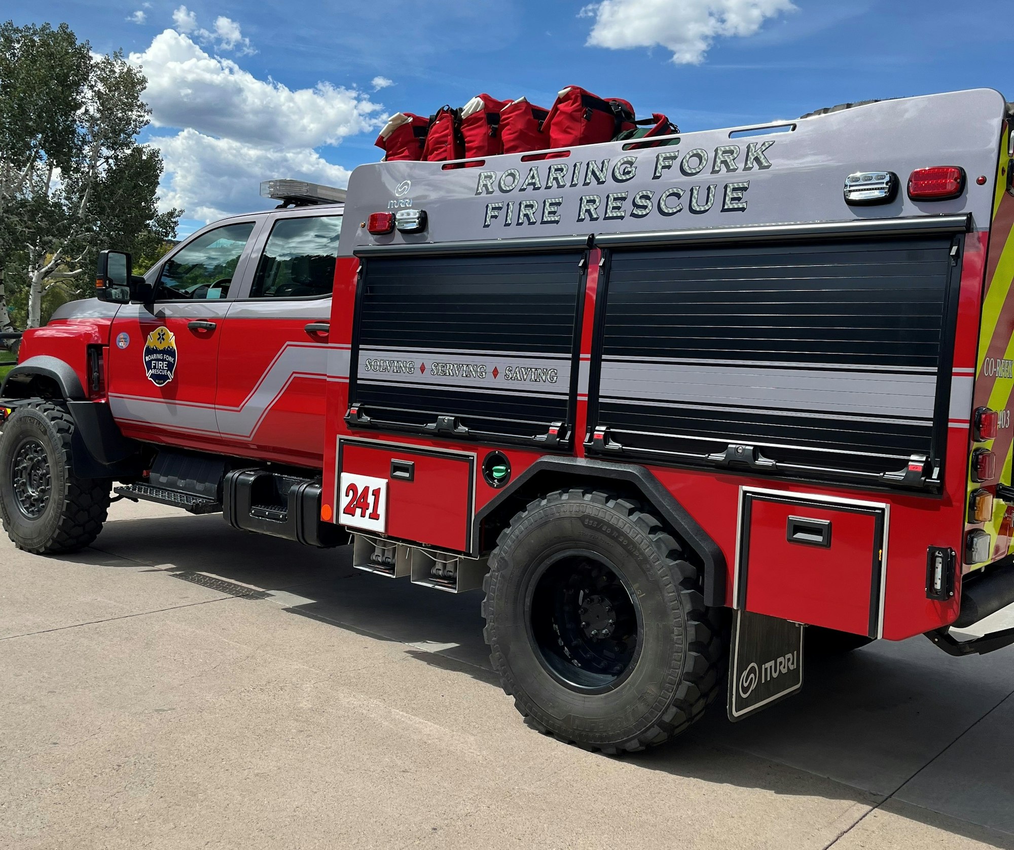 The image features a red fire rescue truck from Roaring Fork Fire Rescue, showcasing its rugged design and equipment storage.