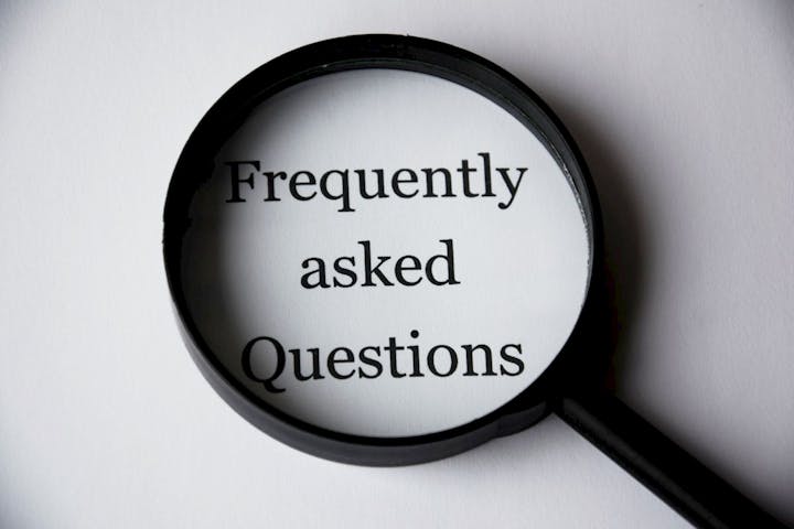 A magnifying glass highlights the text "Frequently asked Questions" on a white background.