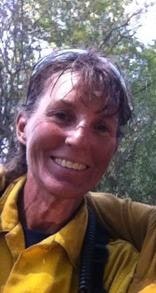 A smiling person in a yellow jacket with wet hair, possibly after rain or exercise.
