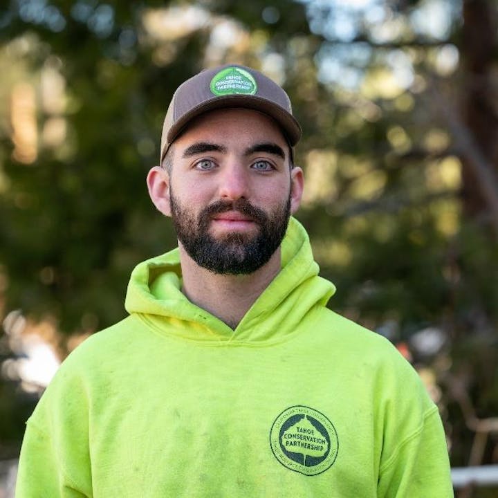 Man with a beard wearing a cap and neon green hoodie, with emblem of Tahoe Conservation Partnership.