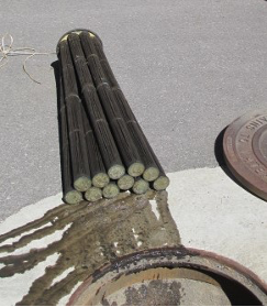 A bundle of cut cables sticking out near an open manhole cover.