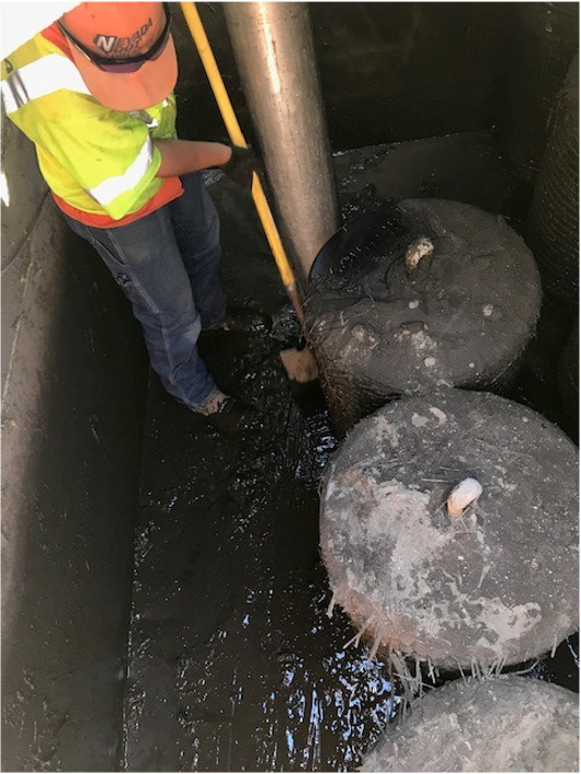 Worker prodding at large frozen discs in a tank with a pole.
