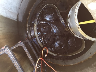 Industrial machinery parts with black grease, wires, and a measuring tape for maintenance or repair.
