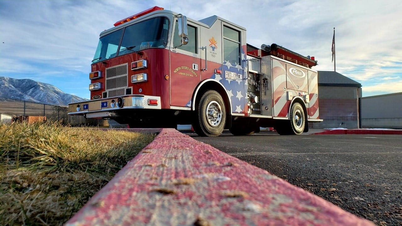 A fire truck parked outside a building, with mountains in the distance and a clear sky above.
