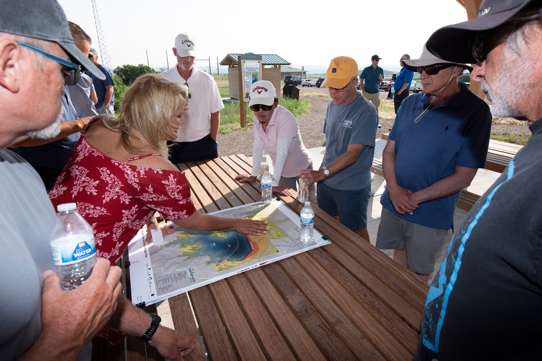 May contain: plywood, wood, baseball cap, hat, cap, clothing, person, woman, adult, female, man, male, sun hat, advertisement, face, head, table, and furniture