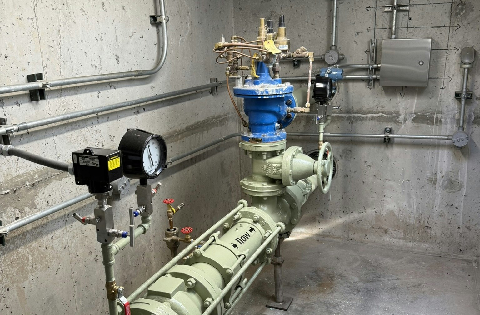 Well vault improvement project with improved electrical equipment showing green pump and pressure gague.