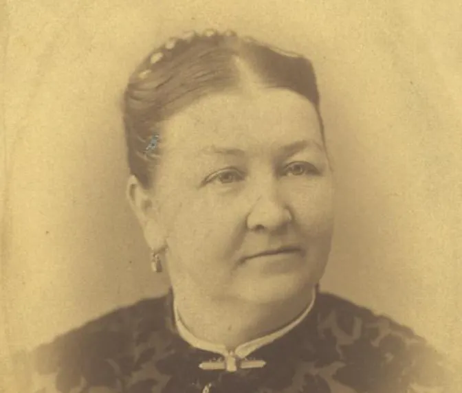 The image shows a vintage portrait of a woman with an elegant hairstyle and a patterned dress, captured in soft sepia tones.