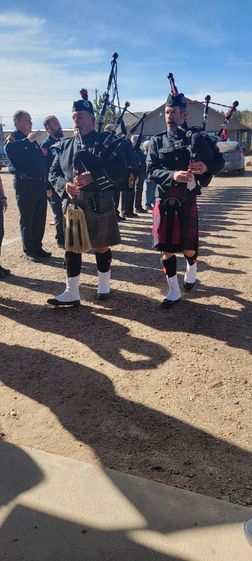Bagpipers in kilts performing beside uniformed personnel.