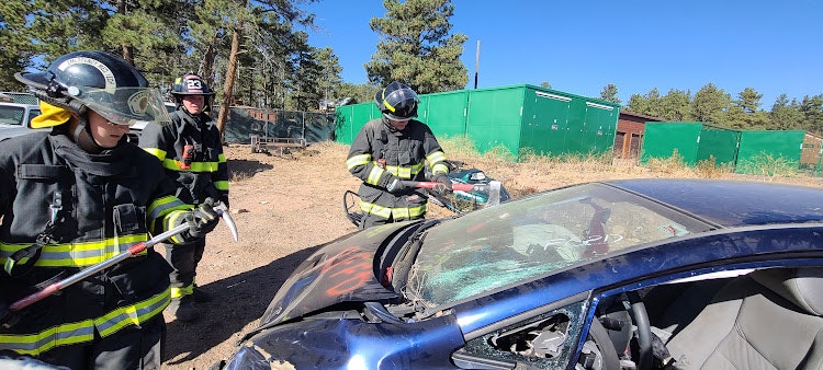 Firefighters training on a car with tools.
