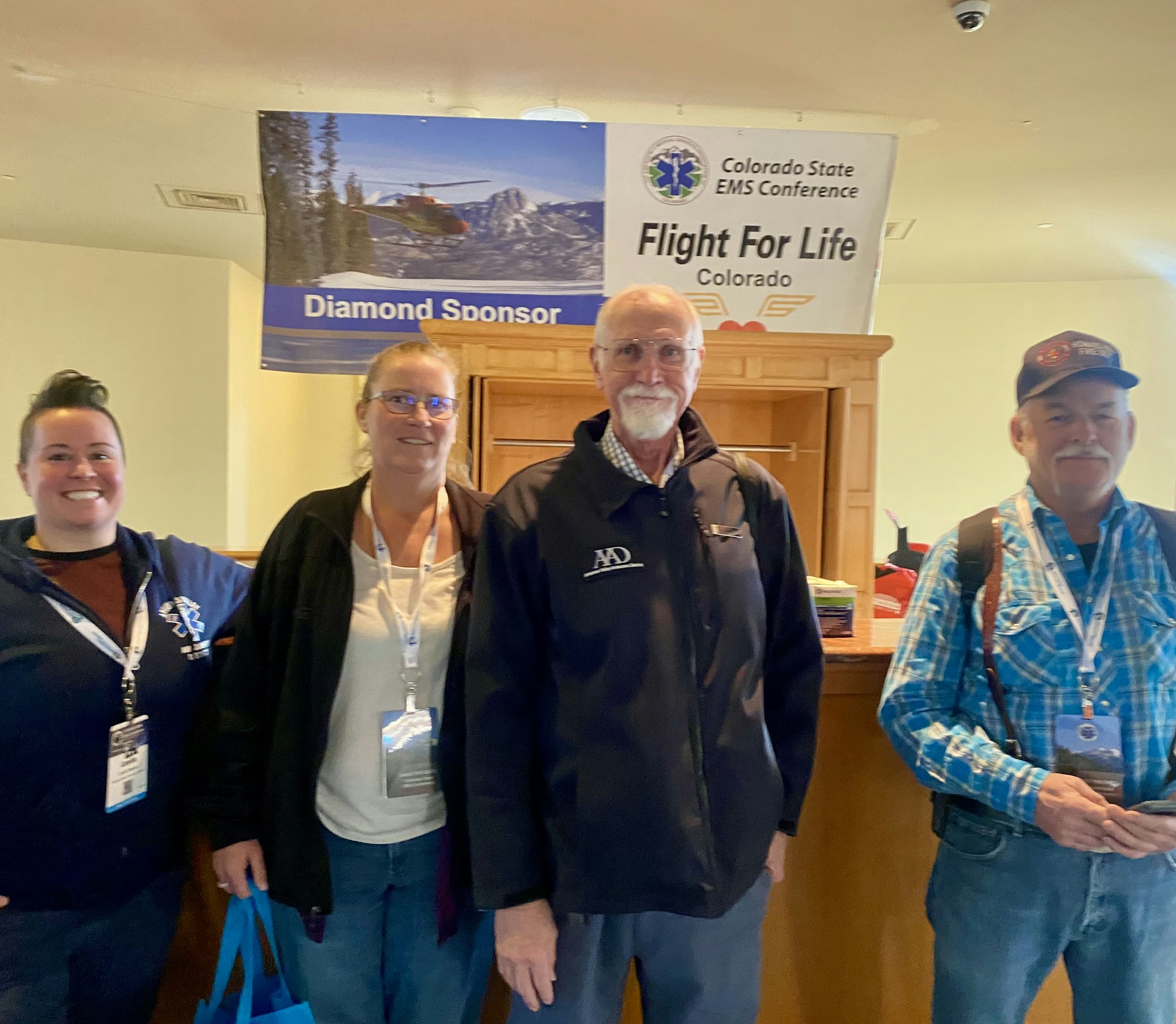 Four people standing in front of "Flight For Life Colorado" banner at an EMS conference.