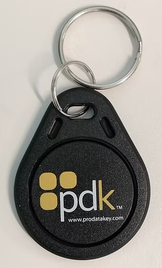 A black key fob with "pdk" logo and website link, attached to a silver key ring.
