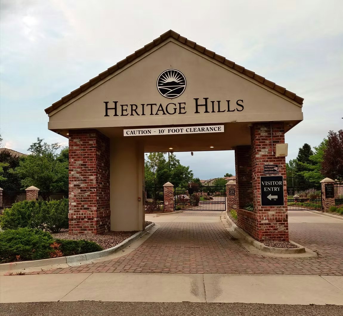 Entrance to Heritage Hills with brick columns, 10-foot clearance warning, and visitor entry sign.