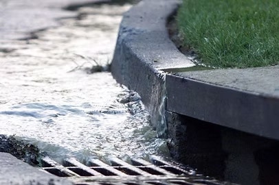 Water flowing into a street drain along a curb.