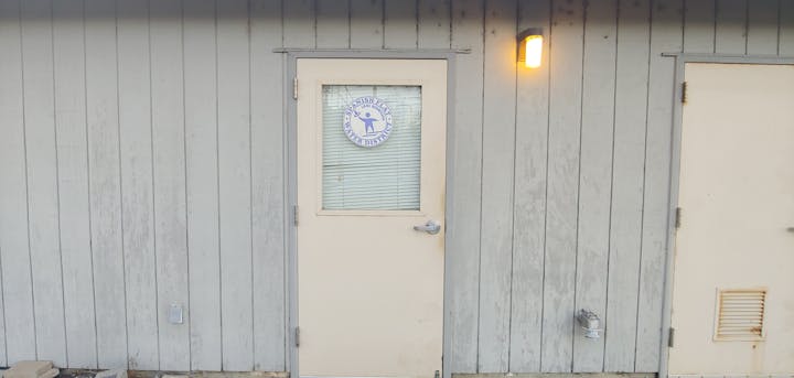The image shows a door with a sign for the Spanish Flat Water District, set against a weathered wooden wall.