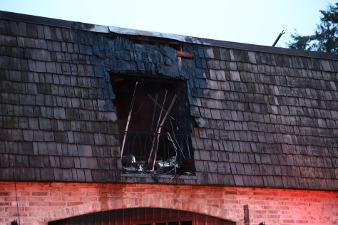 The image shows a damaged rooftop with a charred area, likely from a fire, revealing blackened wood and debris.