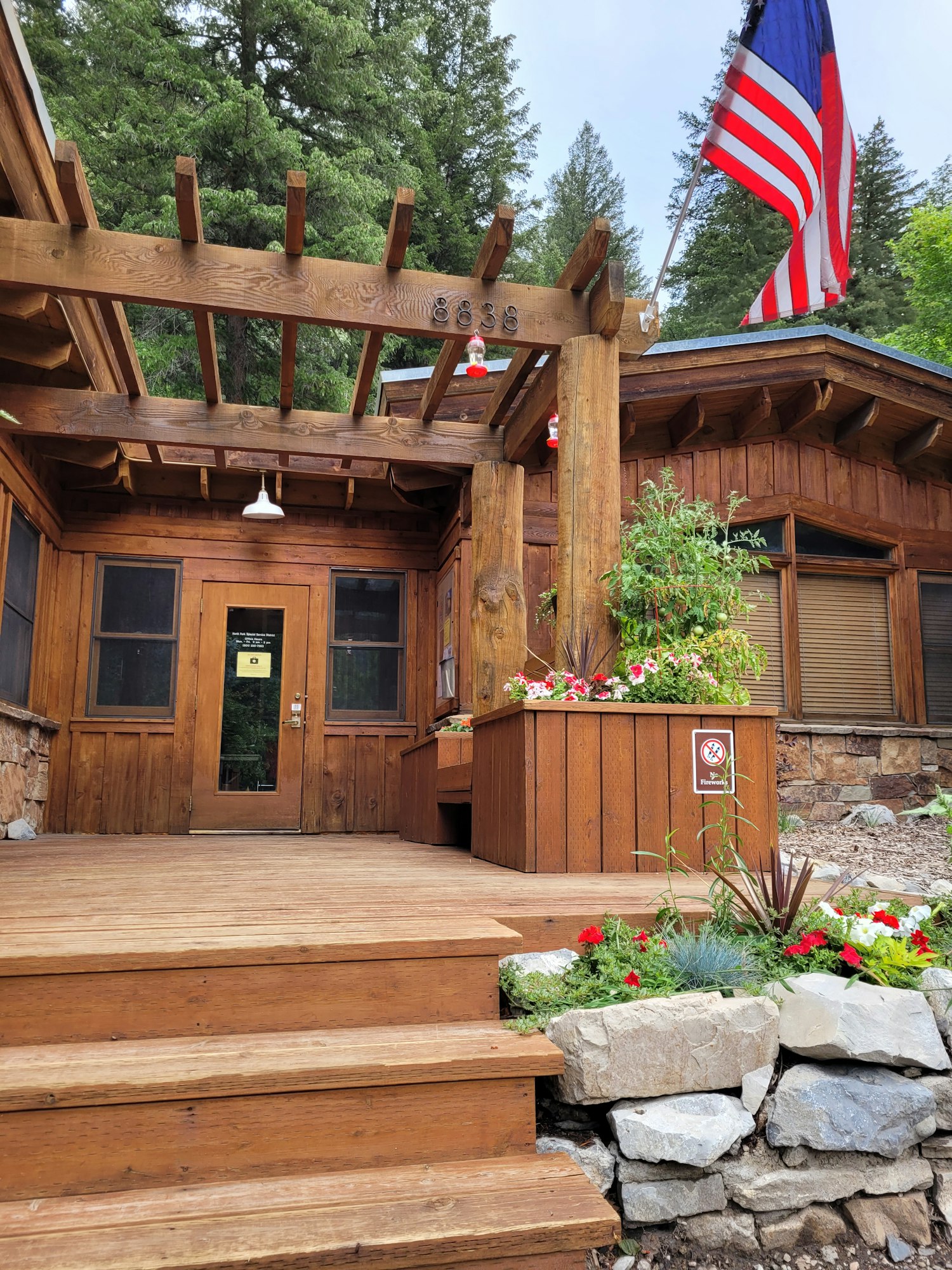 A log cabin with an American flag, flowers, and a no-smoking sign.