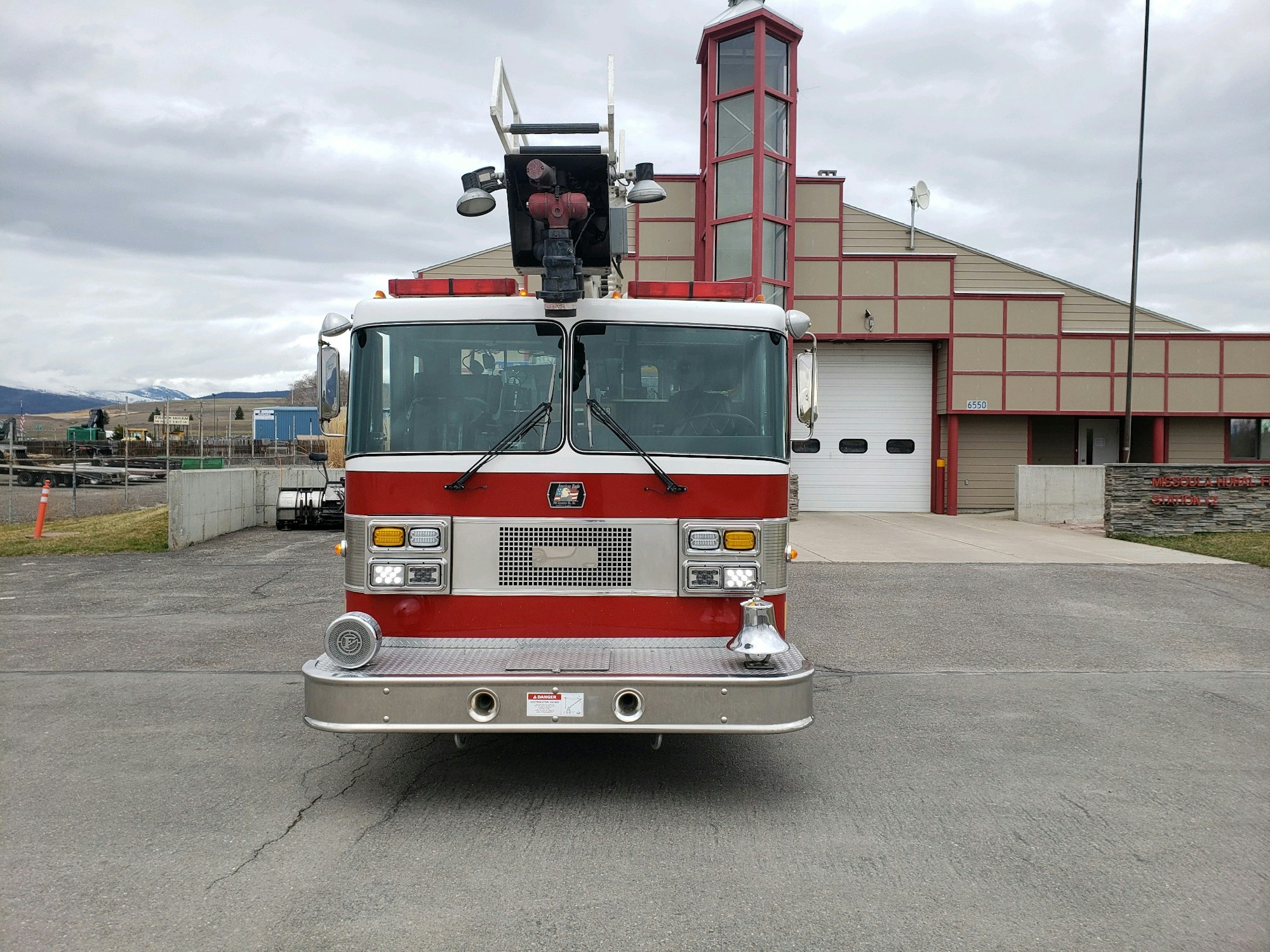 A red fire truck is parked in front of a fire station.