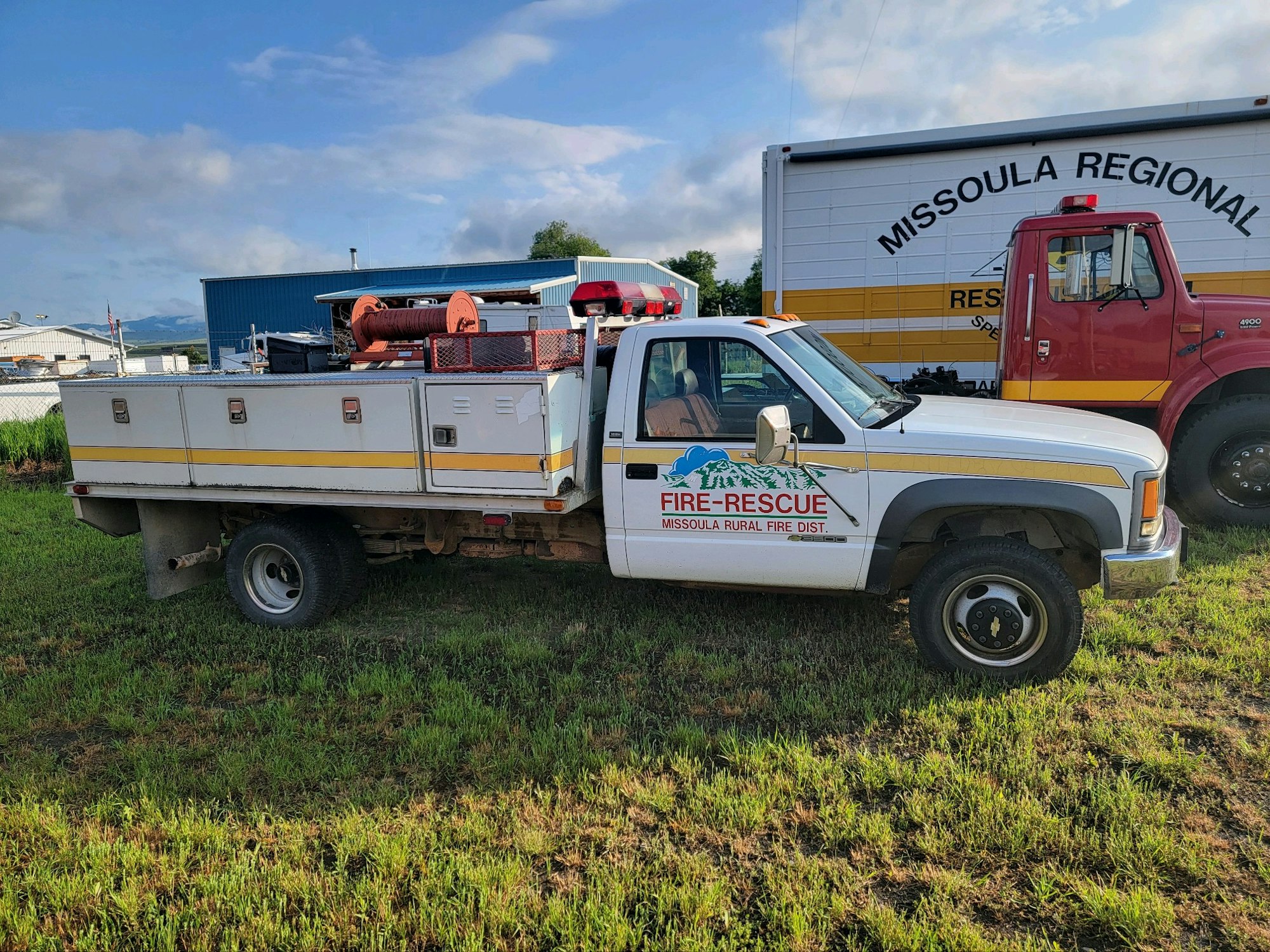 A fire-rescue truck from the Missoula Rural Fire District parked on grass, next to a larger rescue vehicle.