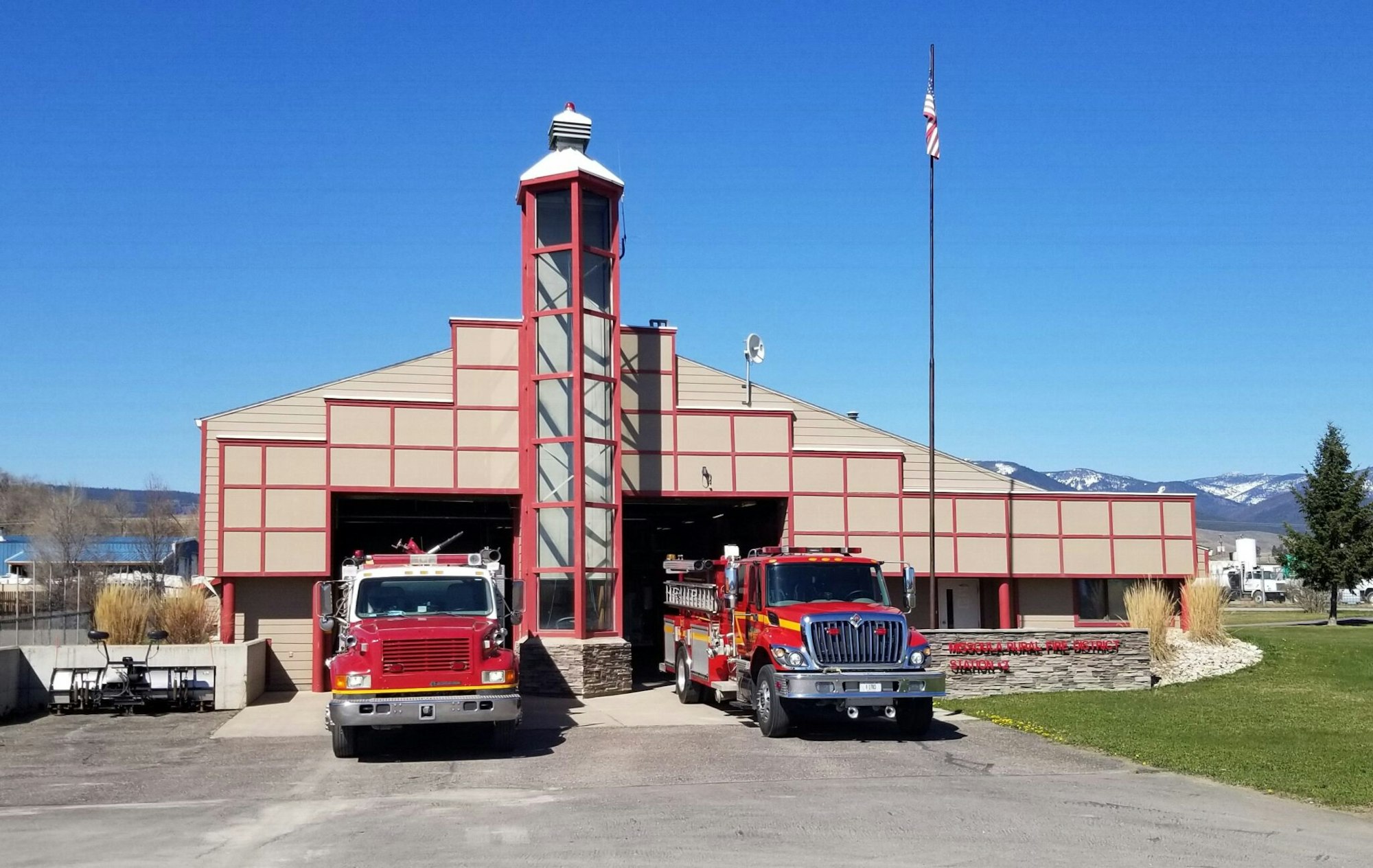 Fire station with two fire trucks parked in front.