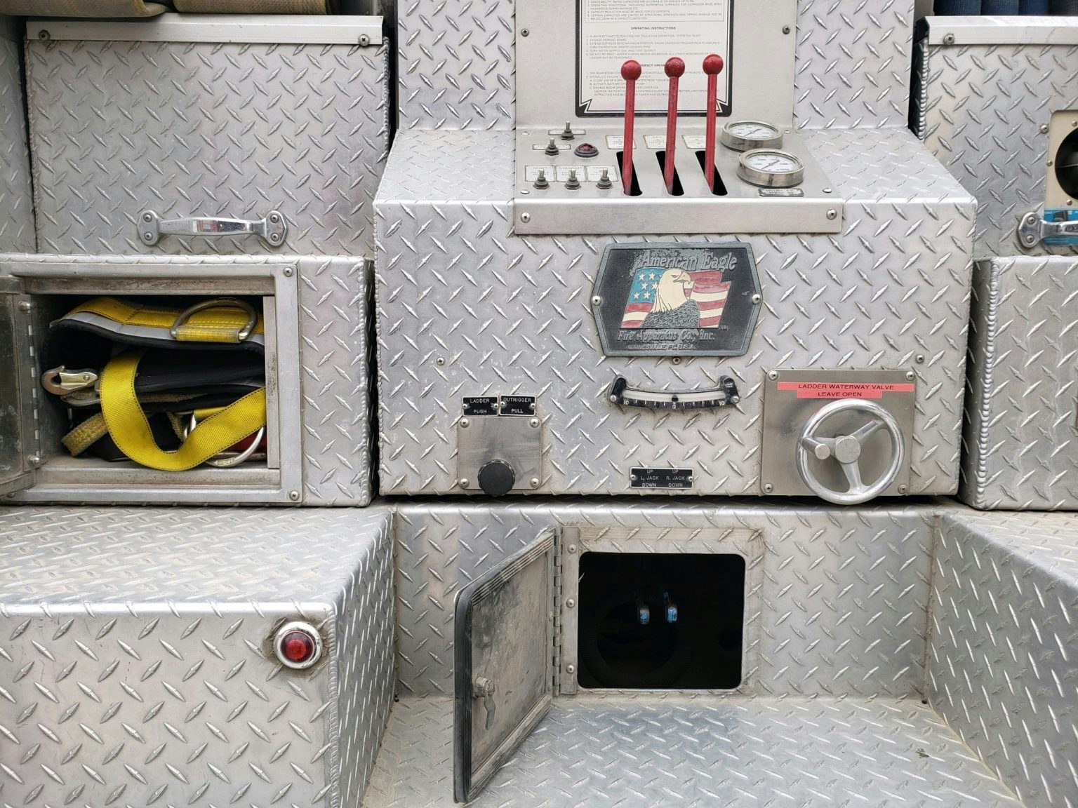 Metal control panel with levers, gauges, and compartments; American Eagle emblem and yellow straps visible.