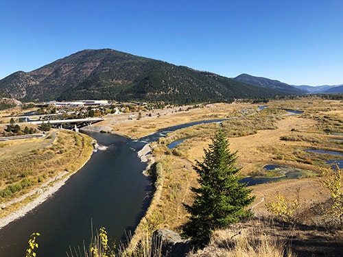 River winding through a valley with distant mountains and clear blue sky.
