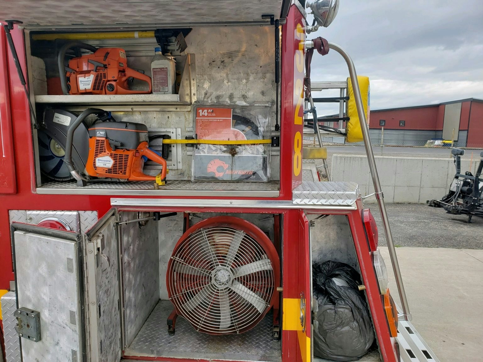 Fire truck compartments with equipment, including saws, a fan, and other tools.