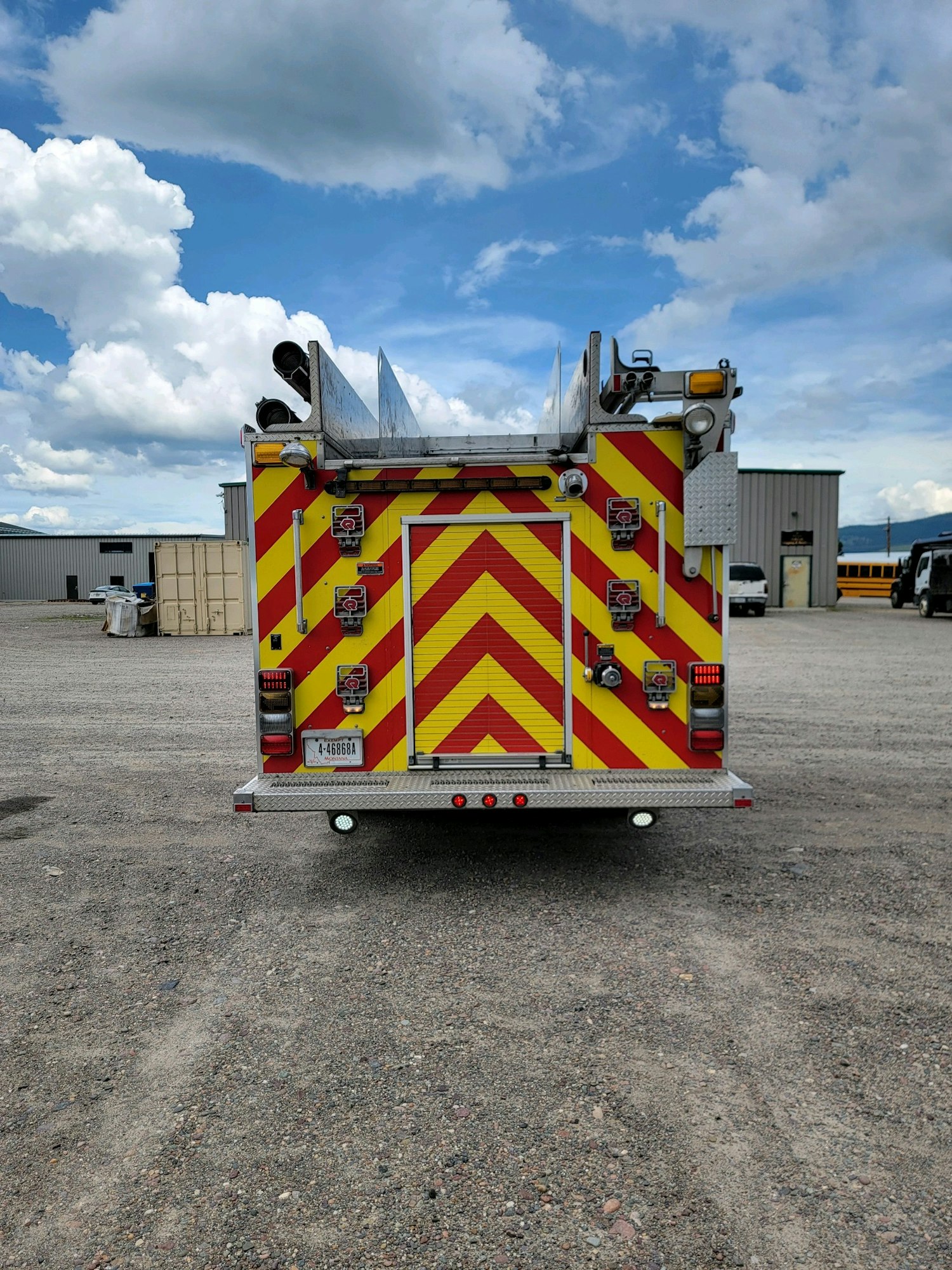 The image shows the back of a fire truck with red and yellow chevron stripes, parked outdoors.