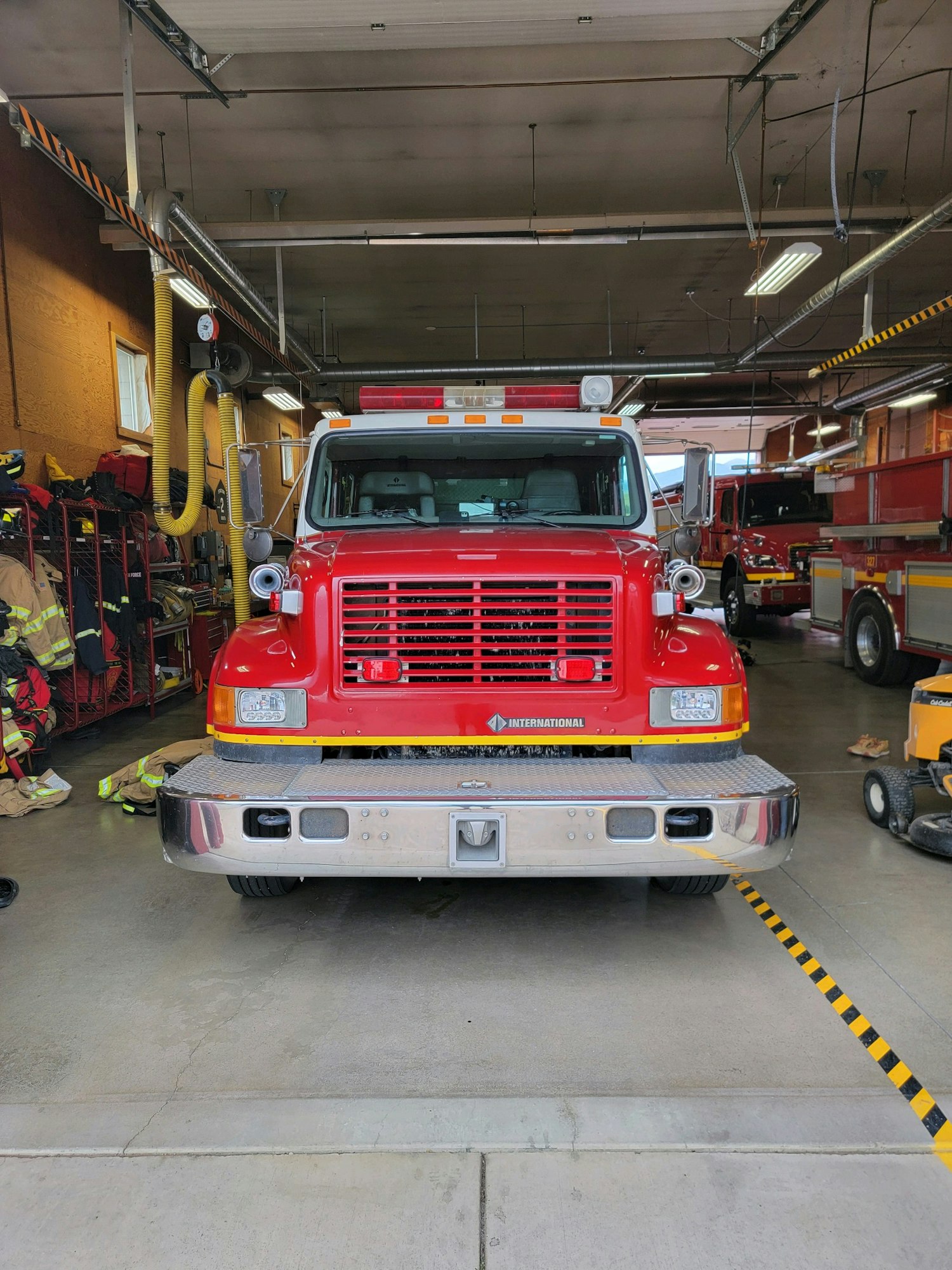 A red fire truck parked in a station garage with equipment around.