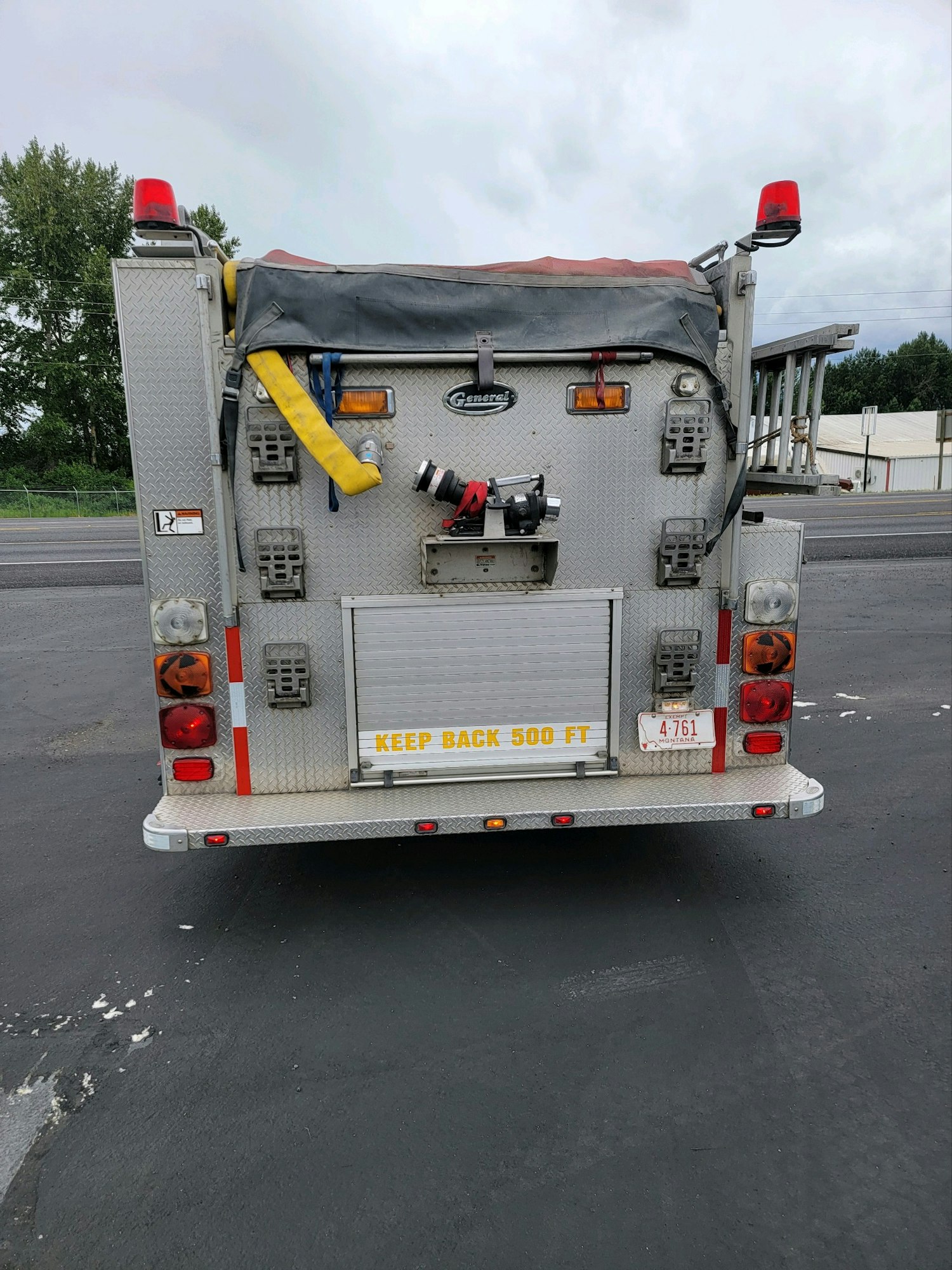 The back of a fire truck with hoses, lights, and a "KEEP BACK 500 FT" sign.